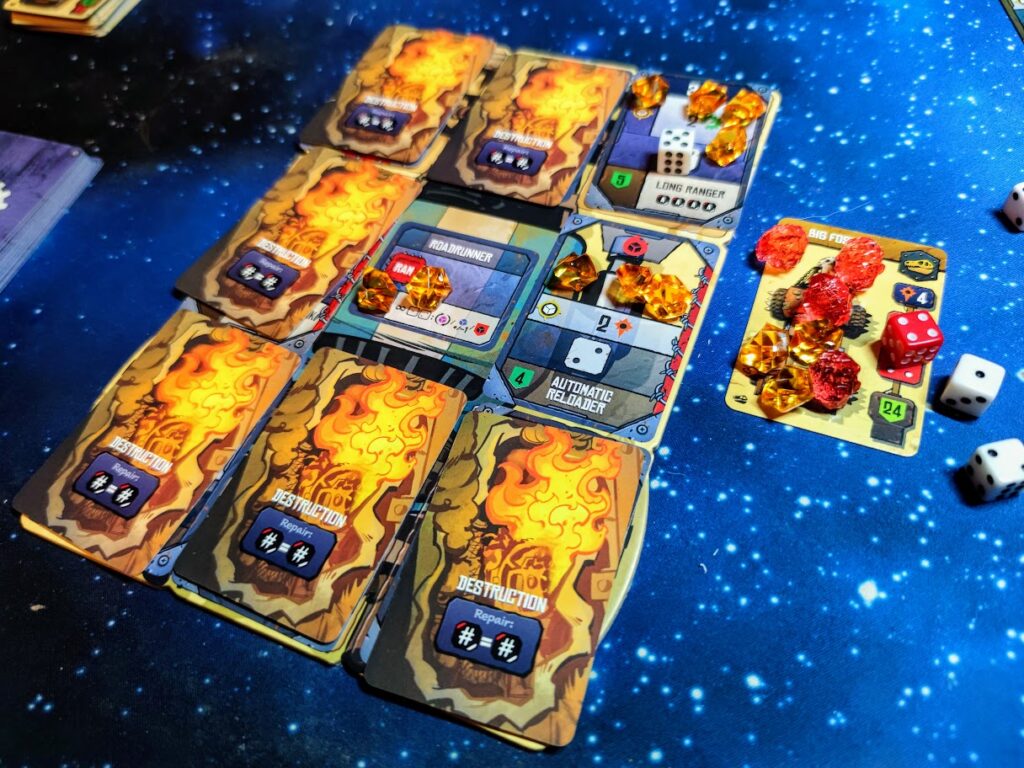 the car mat is covered in cards which show flames of destruction. To the right, the boss car is covered in damage tokens. The game is on a backdrop of a starfield