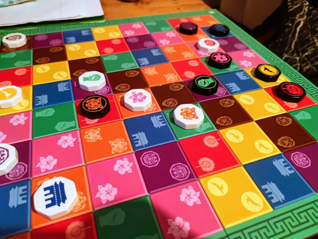 kamisado being played. plkaying pieces tiles are across the board, which is a multicouloured grid of squares